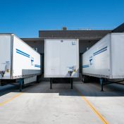 pexels-photo-1267325-1267325 Three white cargo trailers parked at an industrial shipping dock under clear blue skies.